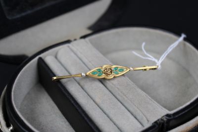 une broche dorée et verte dans un écrin noir