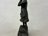 statue of a woman standing on a stone block with her hand on her chin