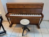 a piano and stool in the corner of a room