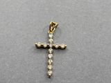 un gros plan d'un pendentif en forme de croix en diamant posé sur une surface grise