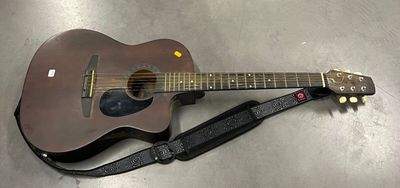 une guitare posée par terre, avec une sangle autour
