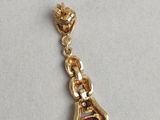 a gold charm with a red stone on it