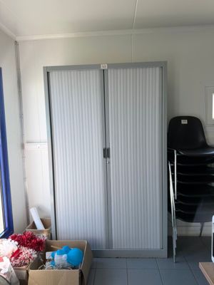 a room with a bed, a desk, a chair, and a refrigerator