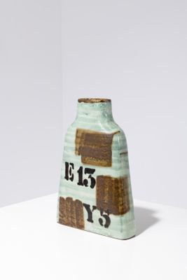 a small green vase with a brown and white design on it