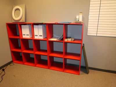 une bibliothèque rouge dans un coin de la pièce
