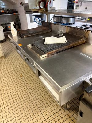 plan de travail en acier inoxydable dans une cuisine professionnelle équipée de fours et de cuisinières