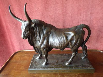 bronze statue of a bull on a wooden table against a red background