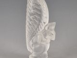 une figurine blanche représentant un chat ailé, posée sur un socle