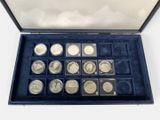an assortment of silver coins in a blue case on a white surface
