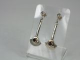 silver earrings with garnets on them on a clear stand
