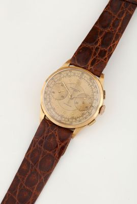 a close up of a watch on a white surface with a brown strap