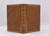 an old book with a brown cover sitting on top of a white table