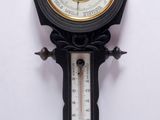 une horloge accrochée au mur, à laquelle est fixé un baromètre
