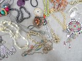 many different types of necklaces and earrings laid out on a table
