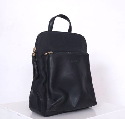 un sac à dos en cuir noir posé sur une étagère blanche
