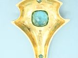 a gold brooch with a blue stone in it
