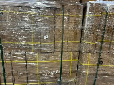 Plusieurs piles de cartons sont empilées les unes sur les autres dans un entrepôt