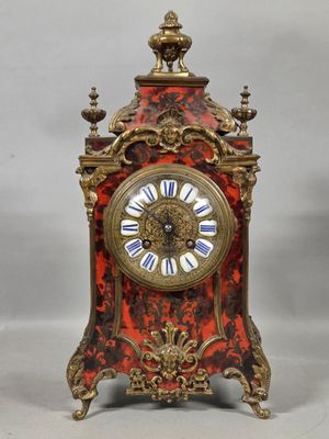 a red and gold clock with a white face