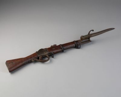 un vieux pistolet avec une poignée en bois sur une surface blanche