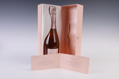 une bouteille de champagne dans un coffret rose, posée sur une table