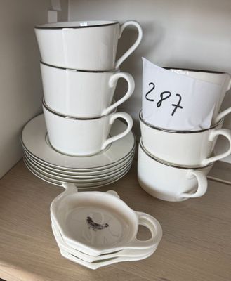 Plusieurs tasses et soucoupes sont empilées sur une étagère dans une cuisine