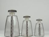 three clear glass salt and pepper shakers with silver lids