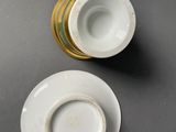 pair of porcelain cups and saucers with gold rims on a gray surface