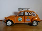 une petite voiture orange sur laquelle est posée une pancarte
