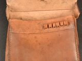 an old brown leather wallet with a metal clasp on a black background