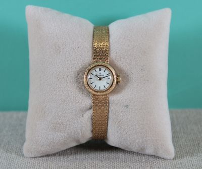 an image of a gold watch sitting on top of a pillow