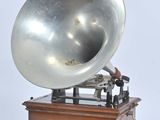 an old silver gramphone on a wooden stand with a white background