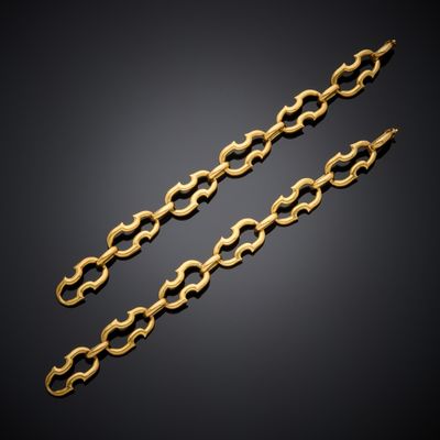a pair of gold chain bracelets on a black background