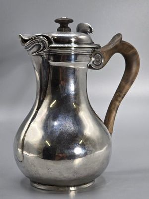 an antique silver coffee pot with a wooden handle on a table