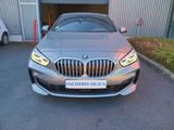 the front end of a silver bmw car parked in front of a building