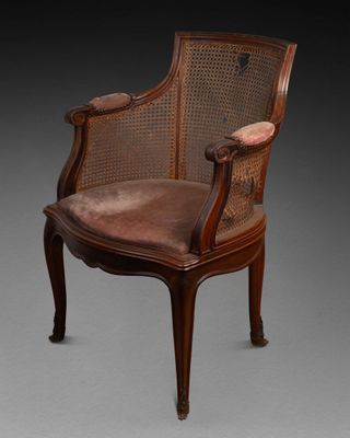 une vieille chaise avec un dossier en rotin et une assise marron