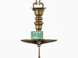 an antique brass candle holder with a green candle on top