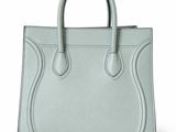 a light green leather handbag with a long handle on a white background