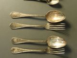 six cuillères en argent sont alignées sur une table
