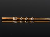 a gold tie bar with three diamonds on a black surface