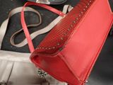 a red purse sitting on a table next to a pair of sunglasses