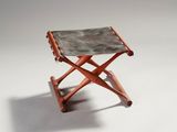 une image représentant un petit tabouret en bois avec une assise en cuir
