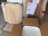 un lavabo blanc posé dans un carton posé par terre