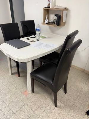 a white table with black chairs and a laptop on top of it