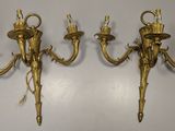 three antique brass wall sconces on a white wall