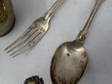 a silver spoon and fork on a table next to a vase