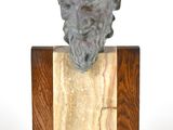 statue représentant la tête d'un homme barbu, posée sur un socle en bois