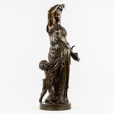 une statue antique en bronze représentant une femme tenant un panier de fleurs