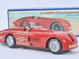 une petite voiture rouge avec un homme au volant, devant une boîte bleue