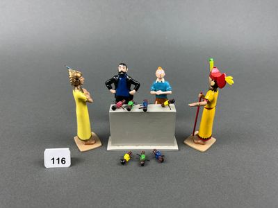 three figurines of people standing in front of a table