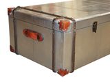 a silver trunk with orange handles sitting on a white surface